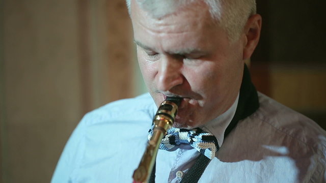 Middle-aged man playing a musical instrument saxophone.
