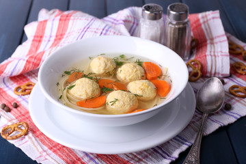 Soup with meatballs and noodles in bowl on wooden background
