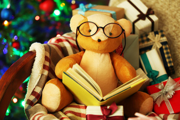 Teddy bear with book and gift boxes in rocking chair