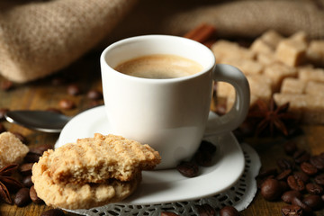 Cup of coffee and tasty cookie on wooden background