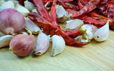 garlic cloves , shallot ,dry chili pepper  on wood cutting boar