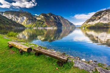 Fototapeta na wymiar Wooden bench at mountain lake in the Alps