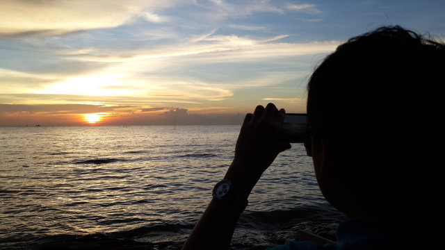 A boy taking photo of the sunset