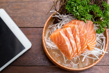 Salmon with a tablet on a wooden table.