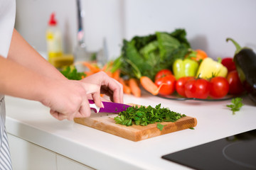 hand with knife cutting food ingredients on wooden board