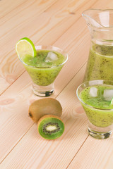 Kiwi juice on the wooden desk closeup.