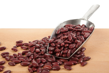 Red kidney beans with scoop on wood table
