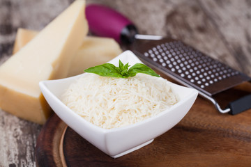 grated parmesan cheese and metal grater on wooden board © Gresei