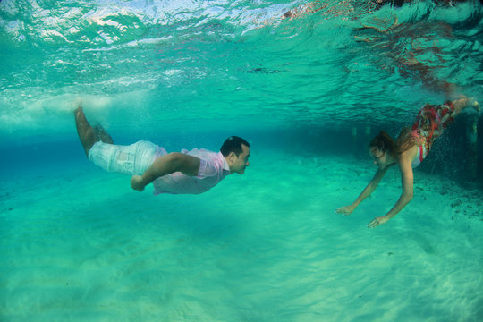 Beautiful man and woman diving dressed