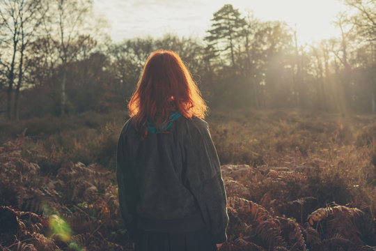 Young woman standing in forest at sunset