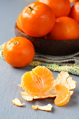 Peeled fresh mandarin with bowl of mandarins