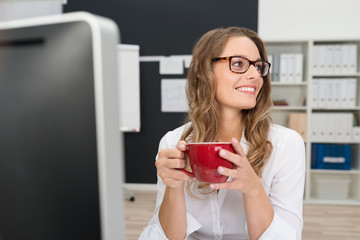 frau mit roter kaffeetasse am arbeitsplatz