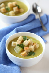 Creamy sweet potato soup with croutons and parsley in white bowl
