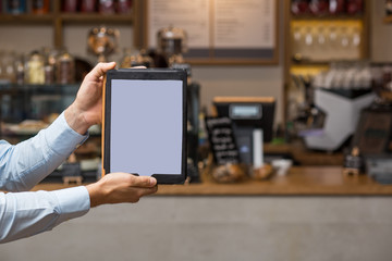 Hand hält Tablet / Hoch / vor Café Kulisse mit Platz für Text