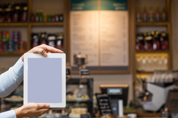 Hand hält Tablet / Hoch / vor Café Kulisse mit Platz für Text