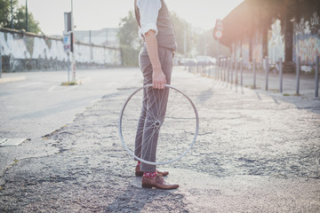 close up of legs shoes hipster man holding old bicycle wheel