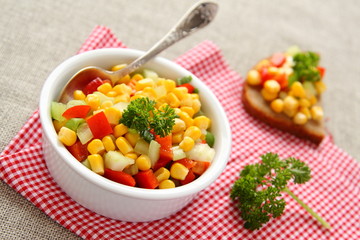 Homemade corn salsa in white bowl with spoon