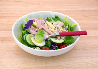 Chef salad with a fork on a wood table top