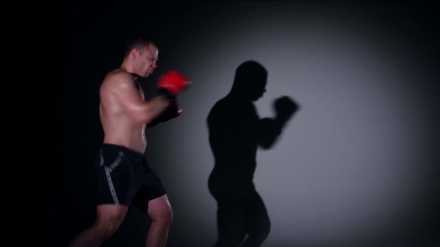 Boxer training shadow boxing over black background
