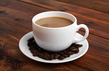 Cup of hot coffee with coffee beans on rustic wooden background