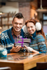 Young couple with gift boxes at the cafe in winter