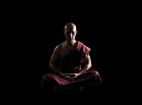Buddhist Monk In Meditation Pose Over Black Background
