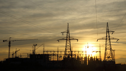 silhouettes of construction and power lines at sunset