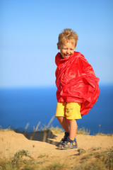 little boy dressed as superhero on the coast