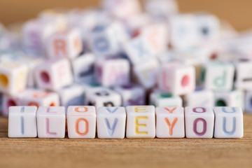 I love you written in letter beads on wood background