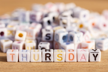 Thursday written in letter beads on wood background