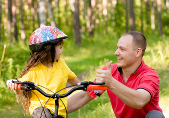 father praises his daughter, who learned to ride a bike