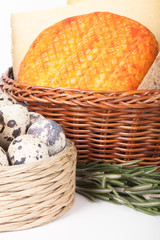 several varieties of cheese in a wicker basket and basket quail