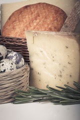 several varieties of cheese in a wicker basket. tinted