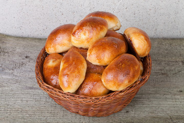 pies with meat or cabbage in a wicker basket on a wooden backgro