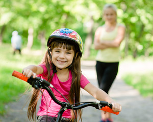 Obraz premium mom and daughter ride bikes in the forest