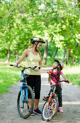 Plakat Happy mother talking with her daughter riding a mountain bike