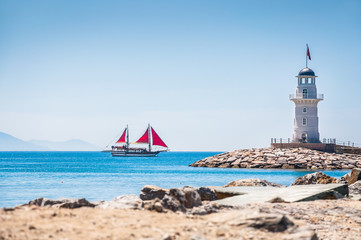 Lighthouse and tourist yacht by the sea - obrazy, fototapety, plakaty