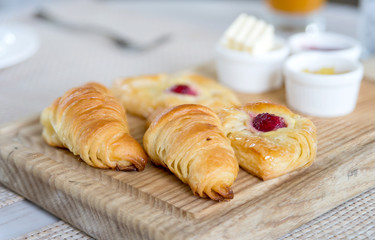 croissants with butter, strawberry jam and pineapple jam in white cup on wooden tray for morning breakfast
