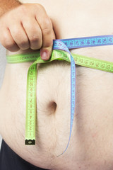 Fat man holding a measurement tape against white background