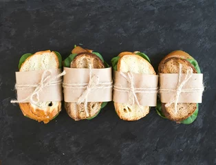 Fototapeten Hühnchen-Spinat-Sandwiches, eingewickelt in Kraftpapier über einem Dar © sonyakamoz