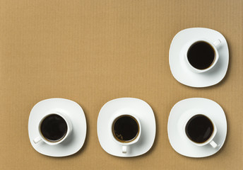 Four full cooffee cups on a light brown background