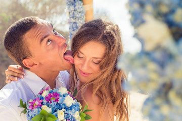 Groom licks bride at a wedding ceremony - obrazy, fototapety, plakaty