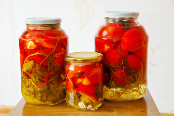 Fototapeta na wymiar three glass jars with marinated tomatoes homemade