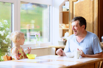 Father and daughter having breakfast in the kitchen