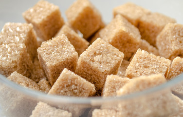 Brown cubes of cane sugar in the glass cup