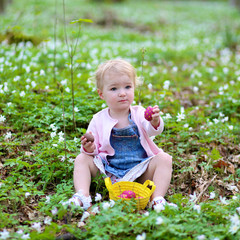 Little girl hunting for chocolate Easter eggs in the forest