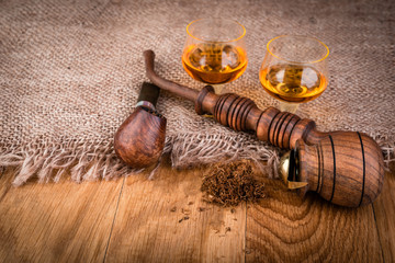 cognac or brandy and smoking pipe on  wooden table