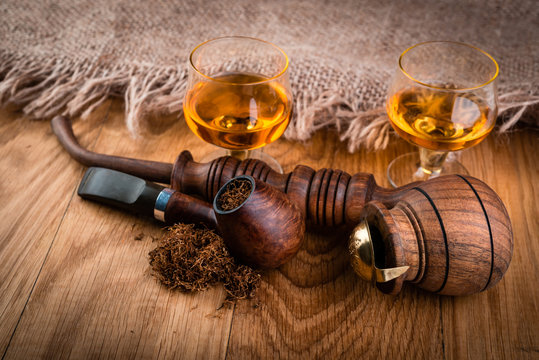 cognac or brandy and smoking pipe on  wooden table