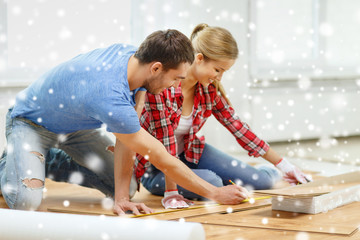 smiling couple measuring wood flooring