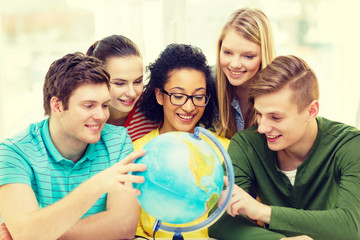 five smiling student looking at globe at school